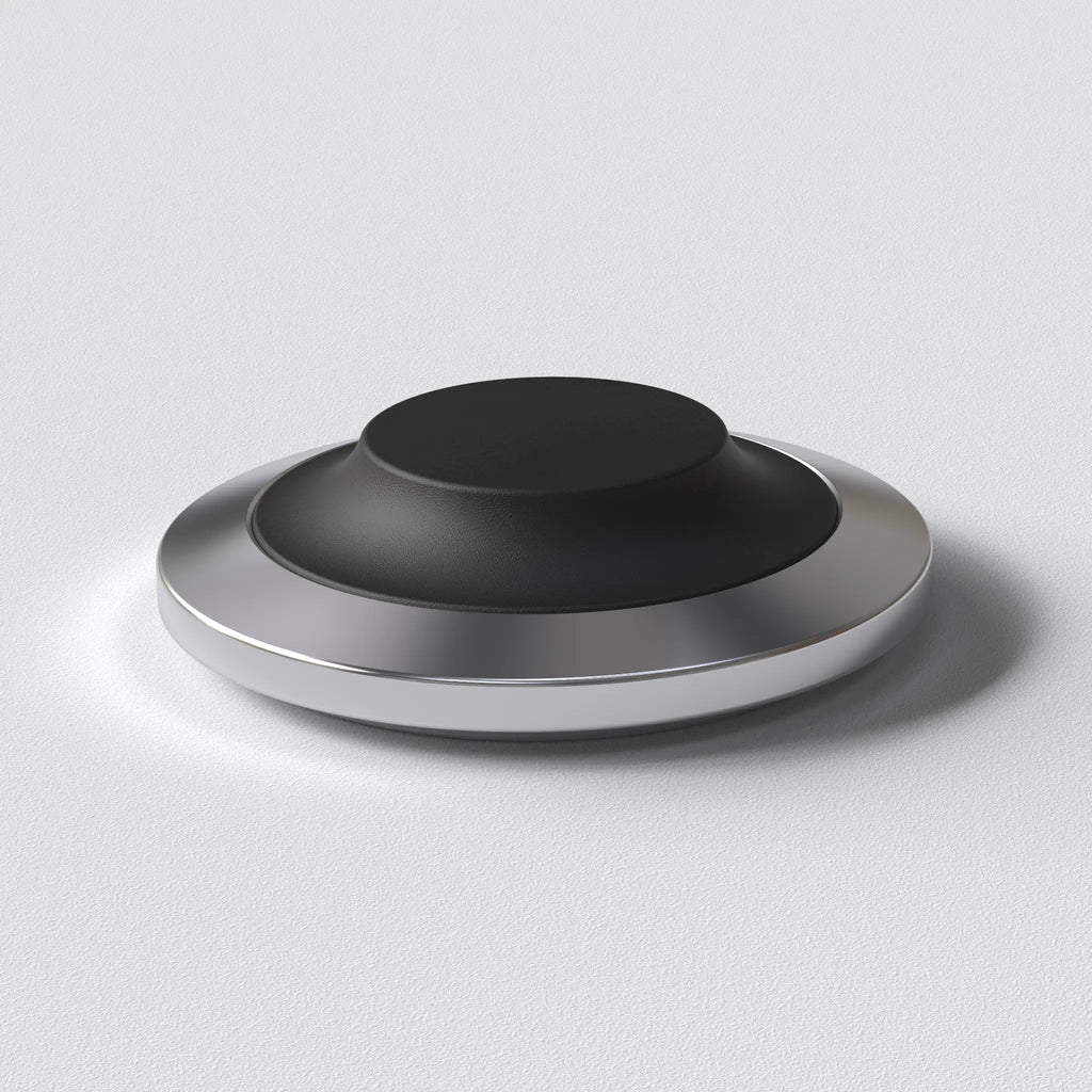 STILL wireless charging dock with a low stainless steel base and replaceable soft cap, designed for a fixed place at home.