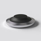 STILL wireless charging dock with a low stainless steel base and replaceable soft cap, designed for a fixed place at home.