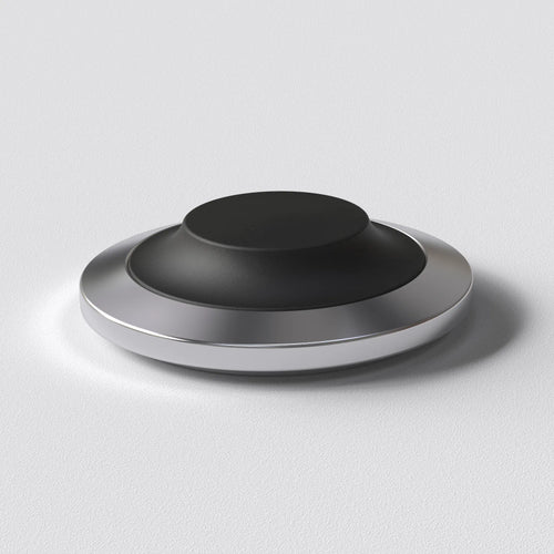 STILL wireless charging dock with a low stainless steel base and replaceable soft cap, designed for a fixed place at home.